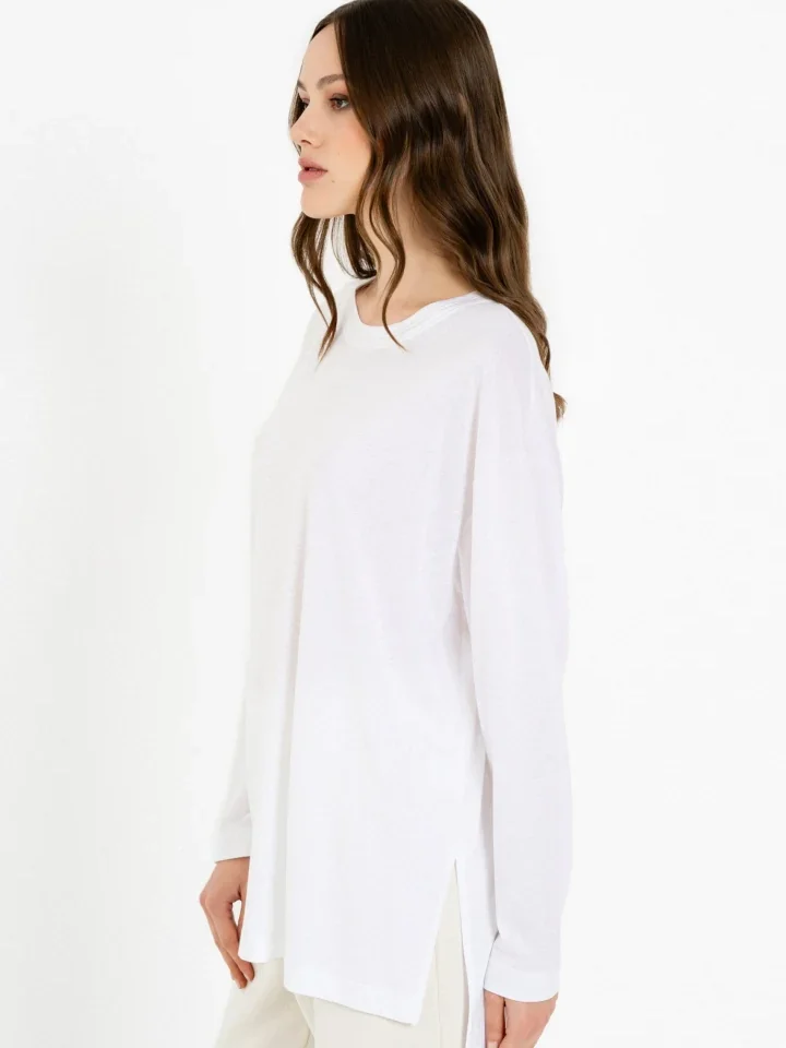 Πλάγια όψη με το μοντέλο να φοράει τη λευκή (White) ριχτή μπλούζα Philosophy Top Organic Jersey, αναδεικνύοντας τη χαλαρή και ρευστή εφαρμογή της.