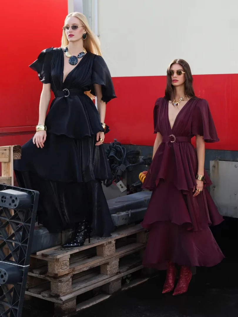 Δύο μοντέλα ποζάρουν δίπλα-δίπλα, αναδεικνύοντας τις δύο εντυπωσιακές αποχρώσεις του φορέματος Nazehda Sarah Dress, σε μαύρο (Black) και μπορντό (Bordeaux).