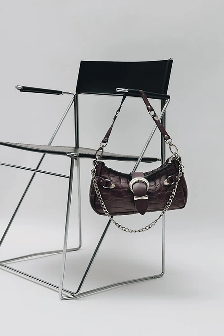 Χειροποίητη δερμάτινη τσάντα Individual Art Leather Kiss of Life Dark Plum Croc κρεμασμένη σε μεταλλική καρέκλα