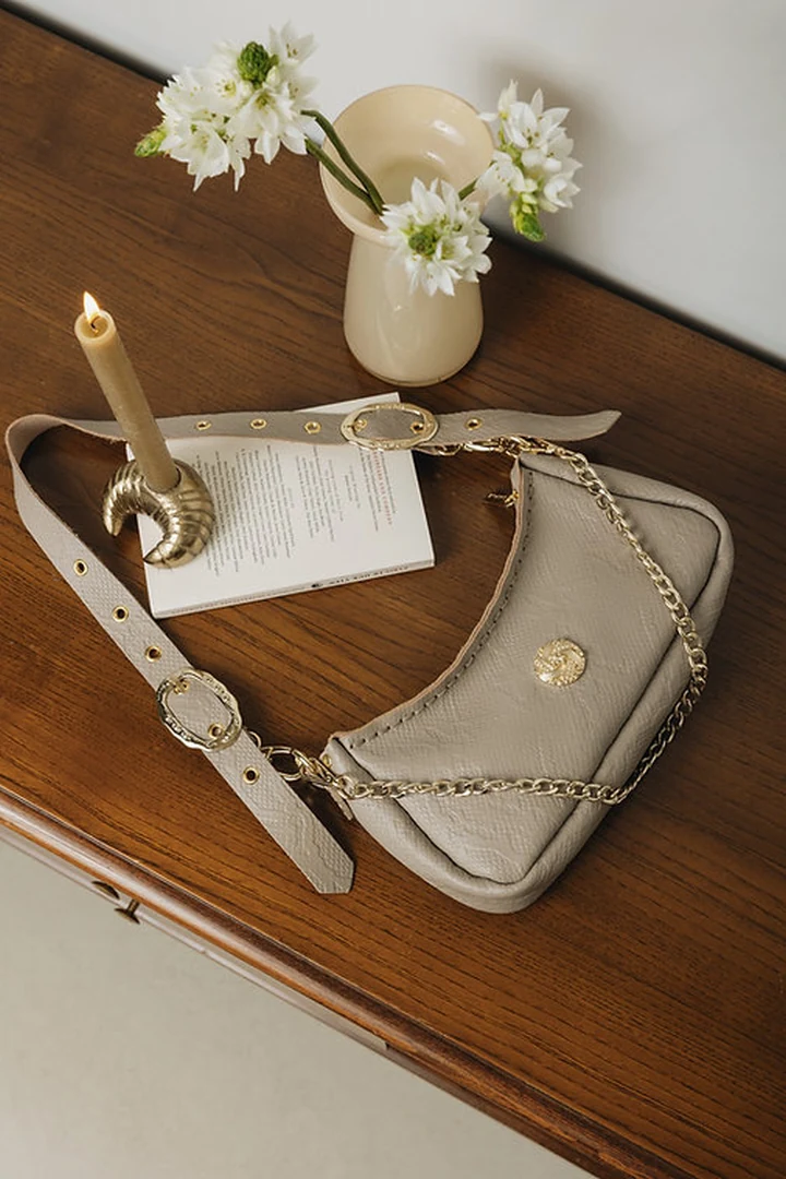 εξωτερική όψη της stone beige δερμάτινης τσάντας individual art leather kashmir που δείχνει την ανάγλυφη υφή και το κεντρικό χρυσό στοιχείο