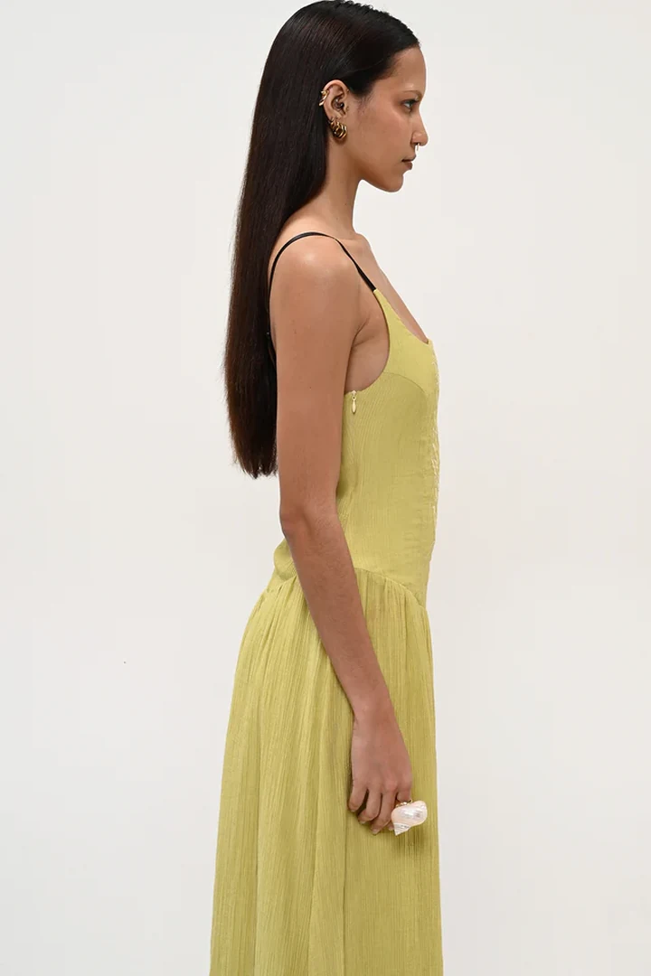 πλάγια όψη με το καλοκαιρινό λαχανί φόρεμα boom lime dress που δείχνει το κρυφό φερμουάρ στο πλάι και την αέρινη γραμμή της φούστας