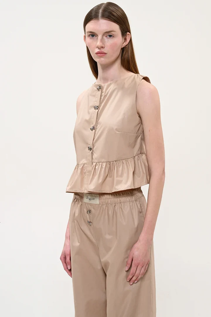 κοντινό πλάνο στο μπεζ cropped top boom που αναδεικνύει τα διακοσμητικά κουμπιά και την κλειστή λαιμόκοψη