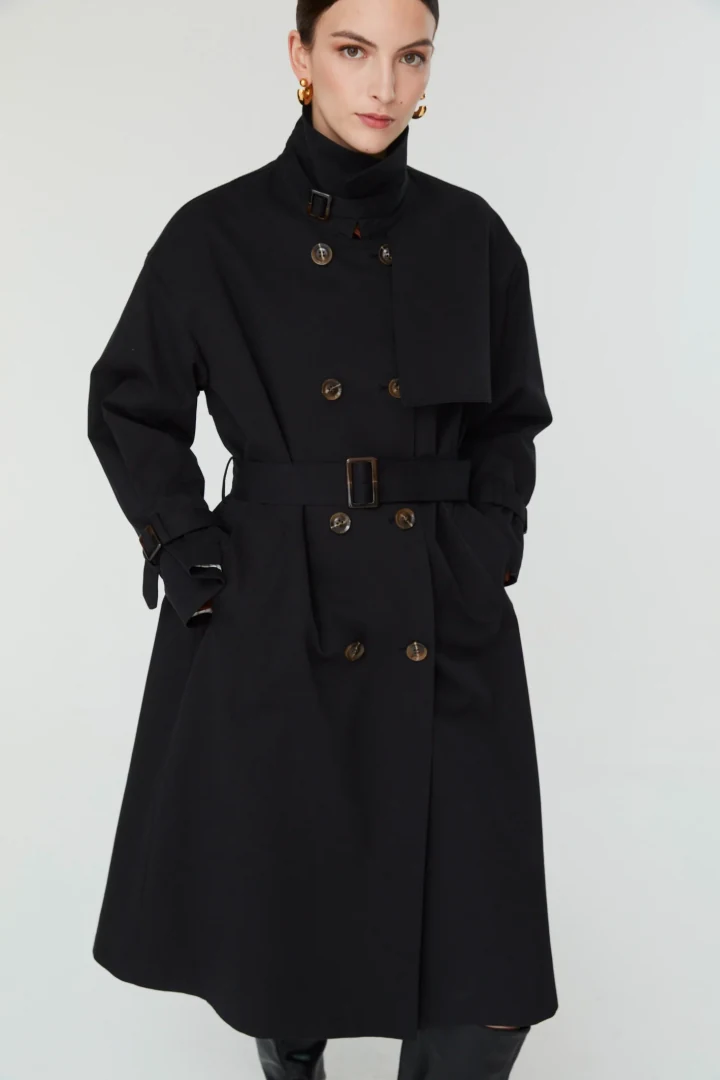 Η γυναικεία καμπαρντίνα Jovonna London Tovallo 2 Trench φορεμένη κλειστή, δεμένη με τη ζώνη της και με τον γιακά όρθιο.