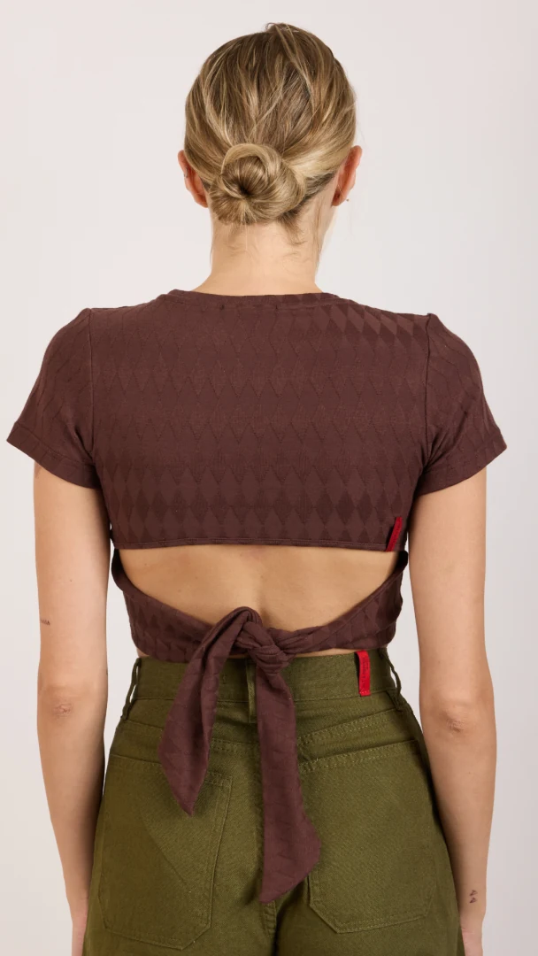Πίσω όψη του μοντέλου που φοράει το καφέ cropped top Salt & Pepper Lena Brown, προβάλλοντας το εντυπωσιακό tie detail με το δέσιμο και το άνοιγμα στην πλάτη.