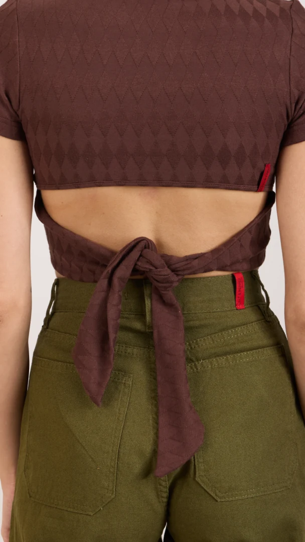 Κοντινό πλάνο στην πλάτη του καφέ cropped top Salt & Pepper Lena Brown, εστιάζοντας στη λεπτομέρεια του δεσίματος και το χαρακτηριστικό κόκκινο ταμπελάκι της εταιρείας.