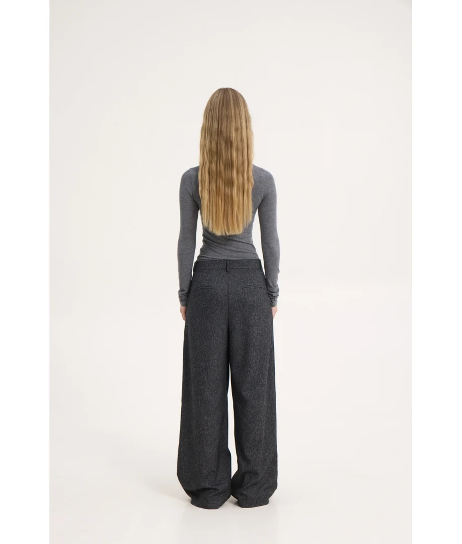 Πίσω όψη του μοντέλου που φοράει το loose fit tailored παντελόνι Sunsetgo Naya Pants, αναδεικνύοντας τη φαρδιά και άνετη γραμμή του